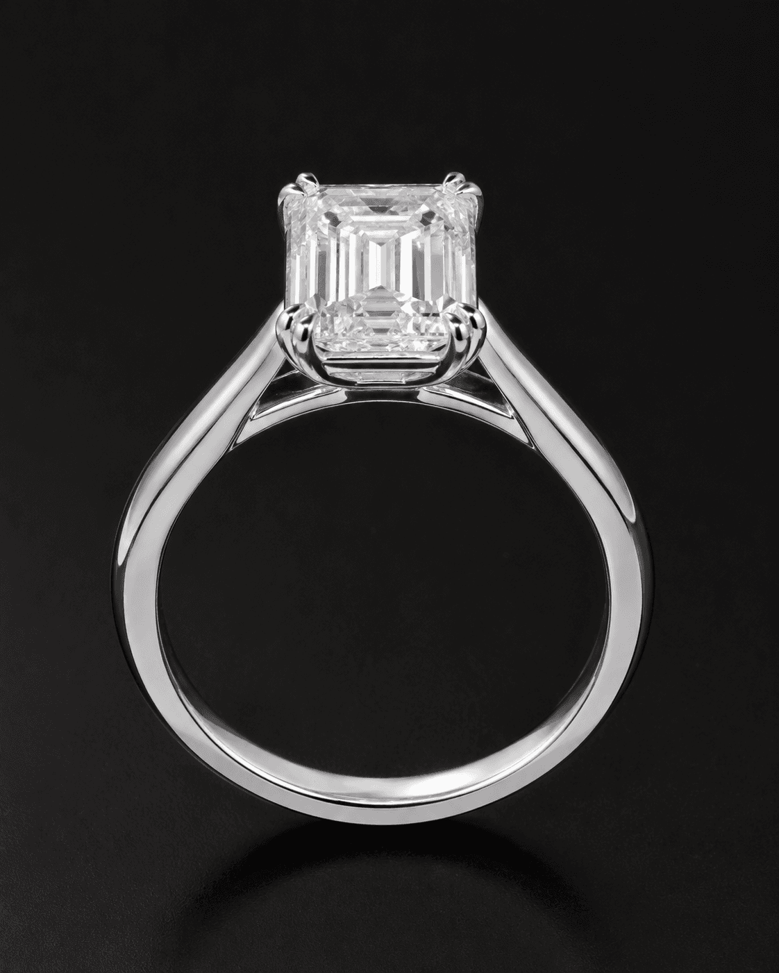 Emerald-cut diamond solitaire ring shown upright to reveal its profile and white metal band